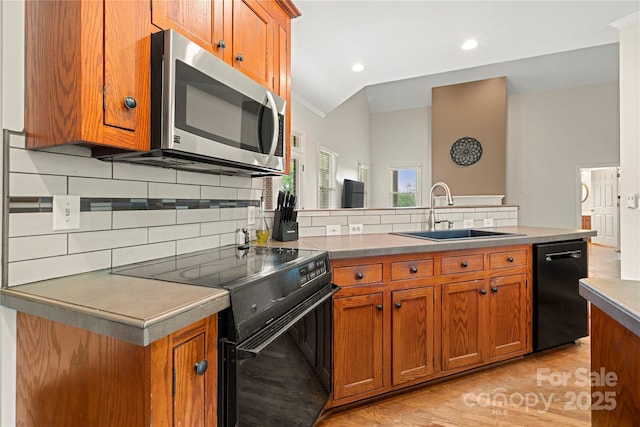 kitchen featuring black appliances, a sink, brown cabinets, decorative backsplash, and crown molding