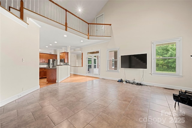 unfurnished living room featuring high vaulted ceiling, baseboards, and recessed lighting
