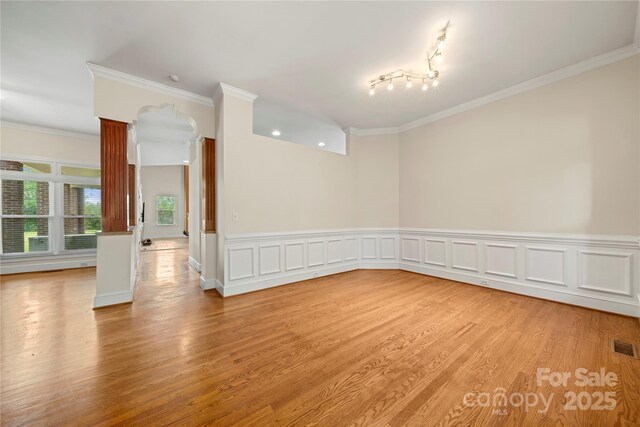 spare room with light wood-style flooring, crown molding, and a wainscoted wall