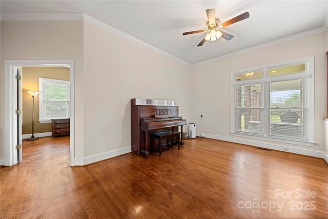 empty room featuring wood finished floors, ceiling fan, baseboards, and ornamental molding