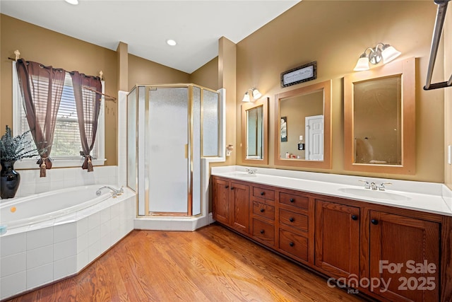 bathroom featuring a garden tub, a shower stall, wood finished floors, and double vanity
