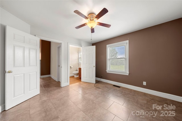 unfurnished bedroom with baseboards, ensuite bath, ceiling fan, and light tile patterned flooring