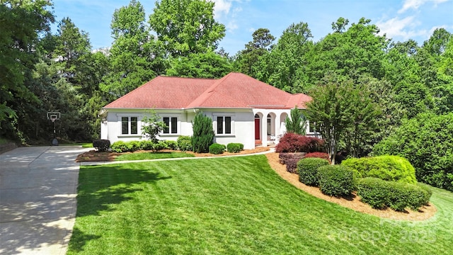 mediterranean / spanish-style home with stucco siding, a front yard, and driveway