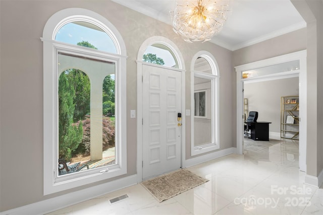 entryway with light marble finish flooring, a chandelier, ornamental molding, and baseboards