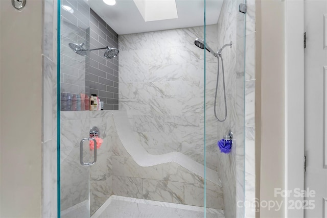 full bath with a marble finish shower and a skylight