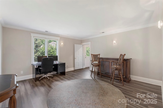 home office with baseboards, wood finished floors, crown molding, and a dry bar