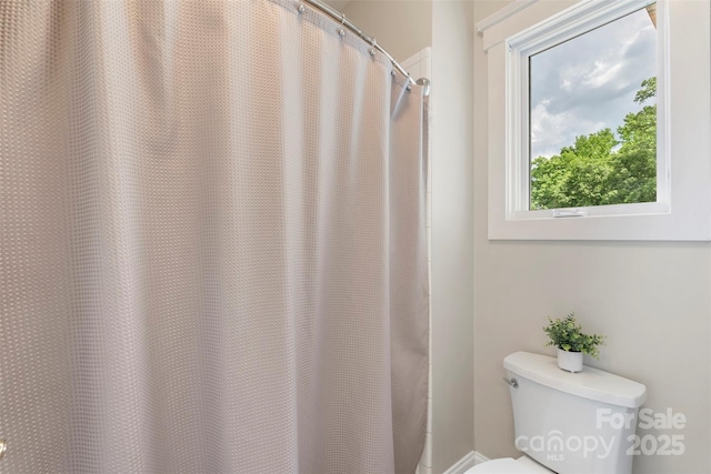 bathroom featuring toilet and curtained shower