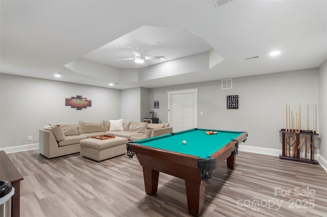 rec room with a raised ceiling, light wood finished floors, baseboards, and recessed lighting