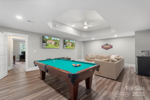 game room with light wood-type flooring, a ceiling fan, a raised ceiling, recessed lighting, and baseboards