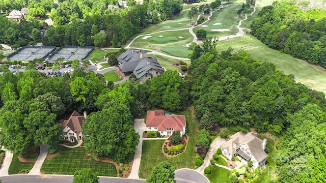 view of property location featuring a golf course, nearby suburban area, and a tree filled landscape