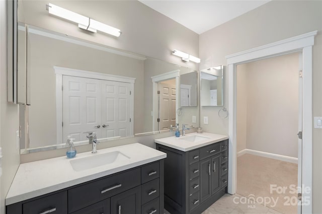 full bathroom featuring two vanities and baseboards
