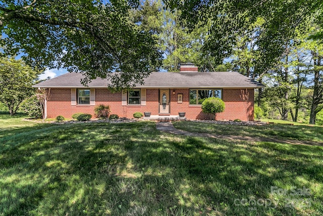 single story home featuring brick siding, a front lawn, and a chimney