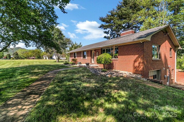 view of property exterior with a lawn, brick siding, a chimney, and a mountain view