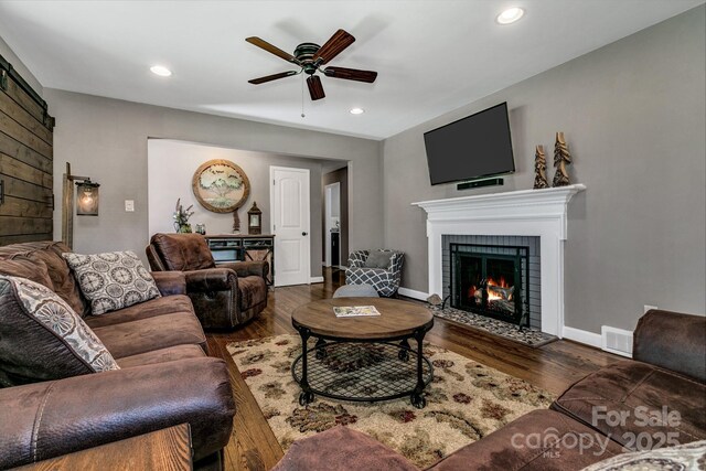 living room featuring a fireplace, a ceiling fan, recessed lighting, wood finished floors, and visible vents