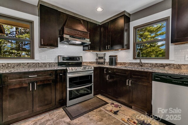 kitchen featuring a sink, appliances with stainless steel finishes, plenty of natural light, and light stone counters