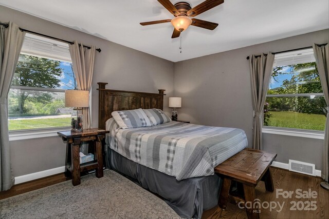 bedroom featuring baseboards, ceiling fan, wood finished floors, and visible vents
