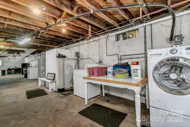 unfinished below grade area featuring water heater and independent washer and dryer
