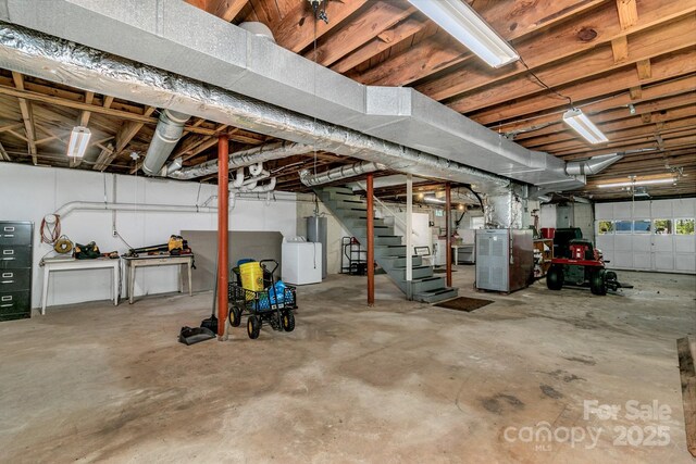 unfinished below grade area with heating unit, independent washer and dryer, and stairway