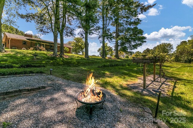 view of home's community featuring a lawn and a fire pit