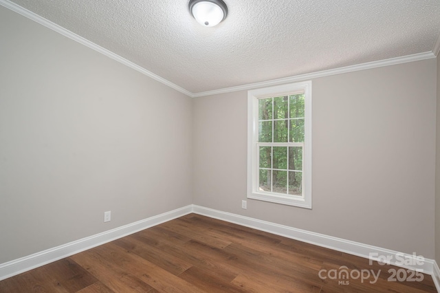 empty room featuring dark wood-style flooring, a textured ceiling, crown molding, and baseboards