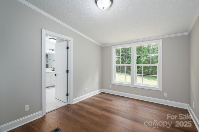unfurnished bedroom with a textured ceiling, baseboards, visible vents, crown molding, and dark wood-type flooring