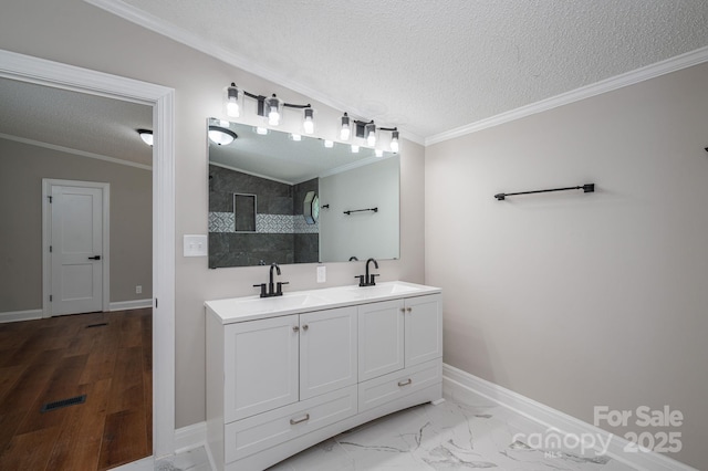 bathroom featuring a sink, ornamental molding, a textured ceiling, and a tile shower