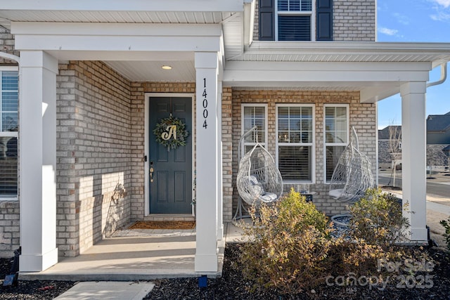 doorway to property with covered porch and brick siding