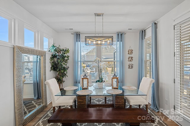 dining area with healthy amount of natural light, wood finished floors, and a chandelier
