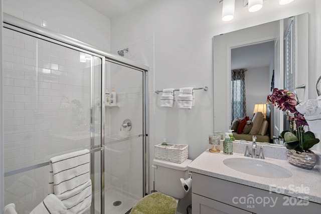 full bath with a shower stall, vanity, and toilet