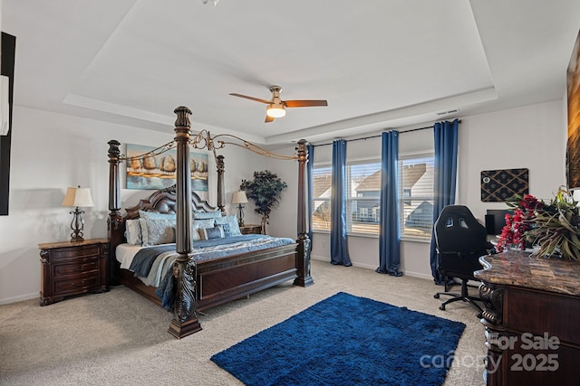 carpeted bedroom featuring a tray ceiling, baseboards, and an office area