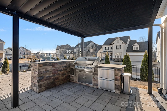 view of patio with a residential view, area for grilling, exterior kitchen, and fence