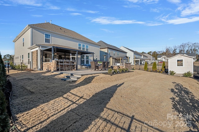 back of property with a residential view, a patio, fence, and an outbuilding