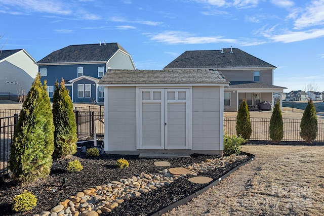 rear view of property with a storage shed, an outbuilding, and a fenced backyard