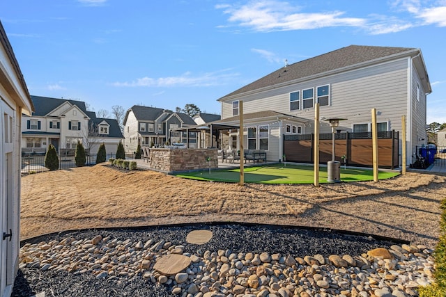 back of house featuring a putting area, a residential view, a fenced backyard, and a patio