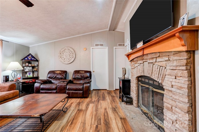living room with lofted ceiling with beams, a textured ceiling, wood finished floors, and a fireplace