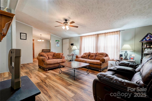 living area featuring crown molding, a textured ceiling, wood finished floors, and ceiling fan with notable chandelier