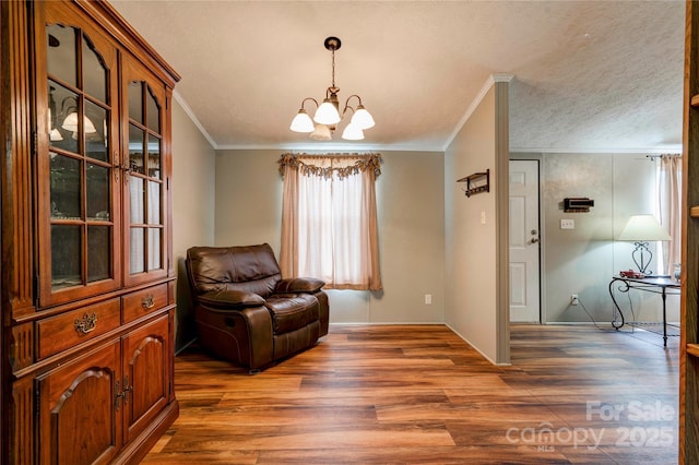 living area featuring wood finished floors, an inviting chandelier, ornamental molding, baseboards, and a textured ceiling