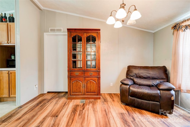 sitting room with light wood finished floors, an inviting chandelier, crown molding, visible vents, and lofted ceiling