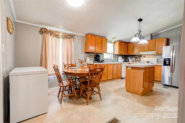 kitchen with fridge, stainless steel fridge, under cabinet range hood, light countertops, and a kitchen island