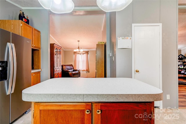 kitchen featuring an inviting chandelier, crown molding, light countertops, pendant lighting, and stainless steel fridge with ice dispenser