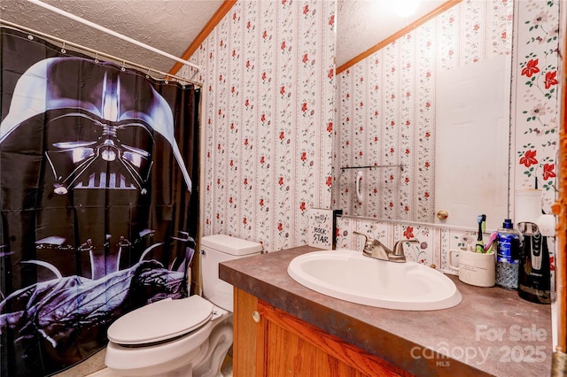 bathroom featuring a textured ceiling, vanity, toilet, and wallpapered walls