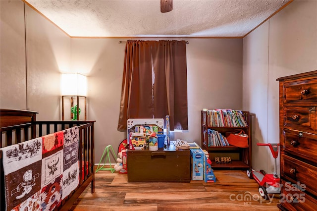 bedroom with a textured ceiling, a ceiling fan, and wood finished floors