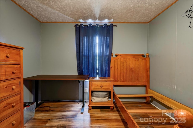 bedroom with a textured ceiling, wood finished floors, and crown molding