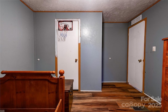 foyer entrance with visible vents, wood finished floors, a textured ceiling, and crown molding