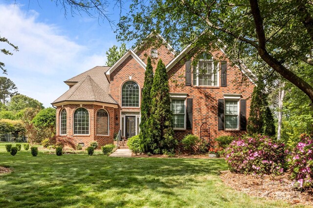 view of front facade featuring brick siding and a front yard