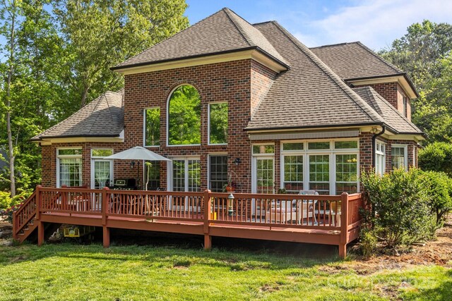 rear view of property featuring a lawn, brick siding, and a shingled roof