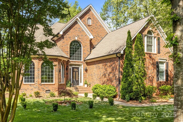 traditional-style home featuring brick siding, a shingled roof, and a front yard