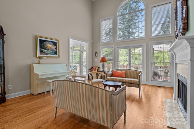 living room with a tiled fireplace, plenty of natural light, and light wood-type flooring