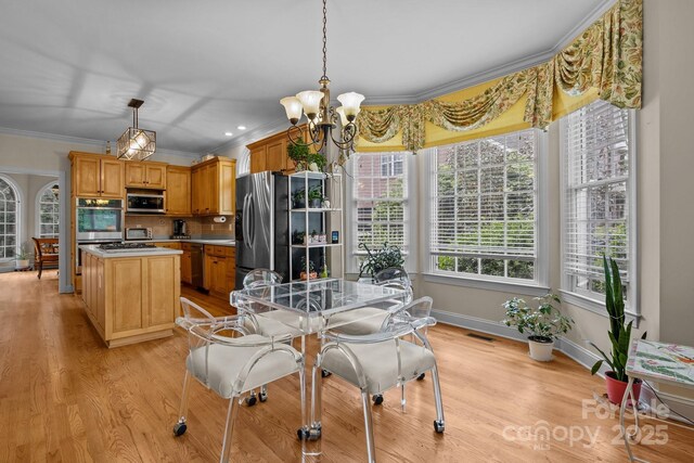 dining room featuring an inviting chandelier, ornamental molding, visible vents, baseboards, and light wood-type flooring