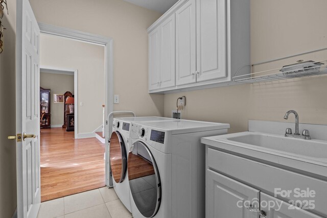 laundry area featuring separate washer and dryer, a sink, cabinet space, and light tile patterned floors